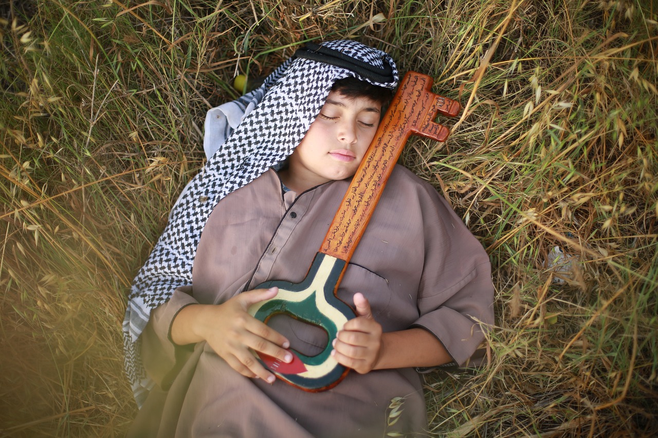 A Palestinian boy finally lying in peace on grass under the cuddling a wooden key that is painted with Palestinian flag colors